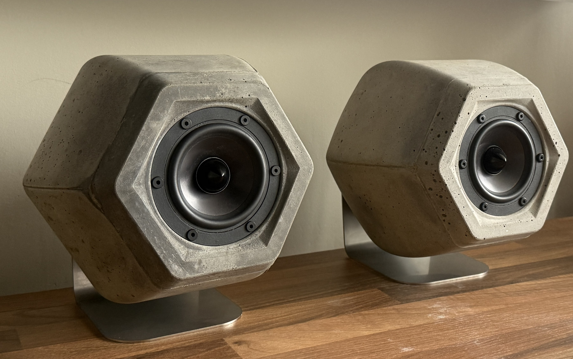 Two Ono speakers on stainless steel stands on a wooden table